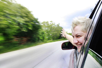 Close-up of cheerful woman looking through car window