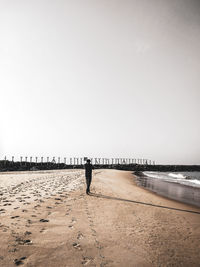 Rear view of man on beach against clear sky