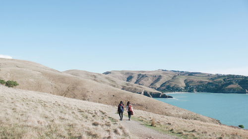 Rear view of men walking on mountain against sky