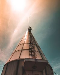 Low angle view of worker climbing on tower against sky