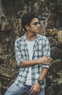 Portrait of young man standing against rock