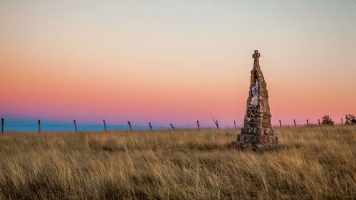 Virgin mary on landscape against clear sky during sunset