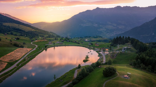 Aerial view at sunrise of lake wolfsee in fiss in summer, on the background the austrian alps