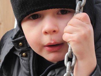 Close-up portrait of cute boy holding chain