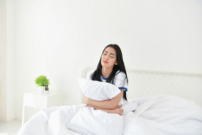 Young woman sitting on bed