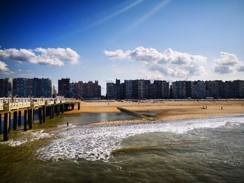 Scenic view of beach by buildings against sky