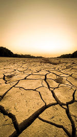 Surface level of barren landscape against sky during sunset