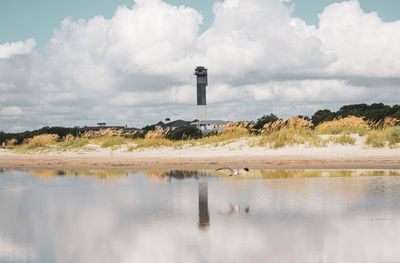 Lighthouse by sea against sky