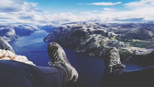 Low section of person on rock against sky