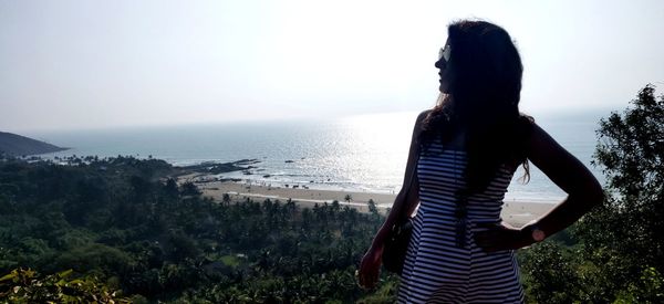 Rear view of man looking at sea against sky