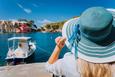 Woman wearing hat in city against sea