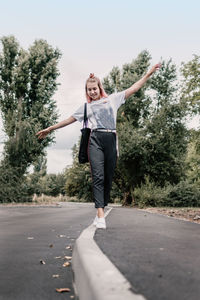 Young man with arms raised while standing on road