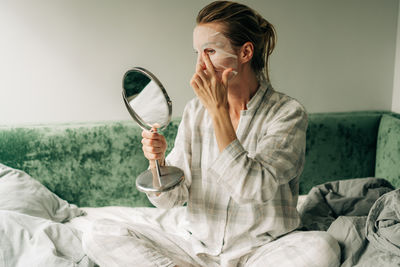 A woman makes a caring beauty procedure at home, a moisturizing cosmetic face mask.