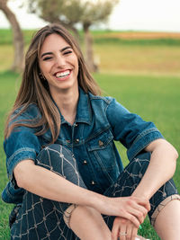 Portrait of young woman sitting on field