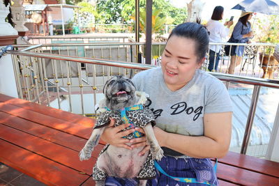 Overweight mid adult woman with dog sitting on bench in park