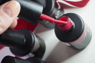 Cropped hand of woman holding red nail polish brush