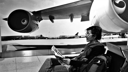 Rear view of man standing by airplane at airport