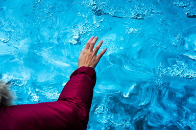 Cropped hand of woman touching blue textured wall