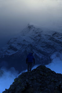 Rear view of people on snowcapped mountain against sky