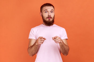 Portrait of young man against orange background