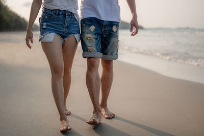 Low section of couple walking on beach