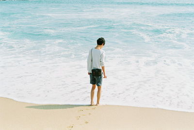 Rear view of boy standing on beach