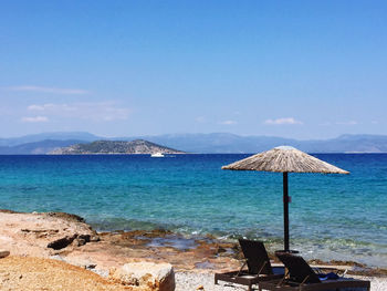 Deck chairs on beach against sky