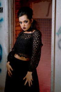 Portrait of woman wearing black dress standing at home