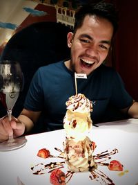 Portrait of young man with ice cream on table