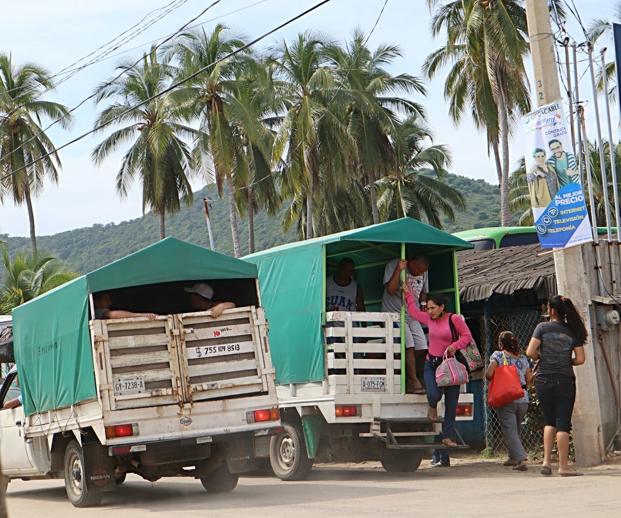 PEOPLE WALKING ON STREET BY PALM TREES