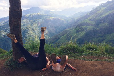 Mother and child lying on field against mountains