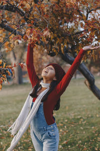 Full length of young woman standing on field during autumn