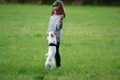 Girl playing with dog on grassy field