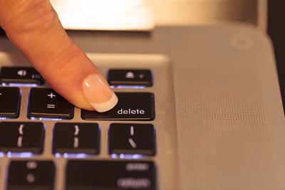 Cropped finger of woman pressing button on laptop