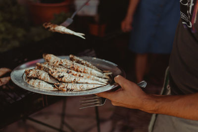 Midsection of man holding fish in plate