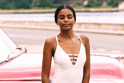 Woman in dress with eyes closed standing against car