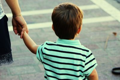 Cropped image of mother holding son while walking on road