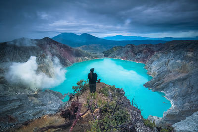 Man looking at waterfall against sky
