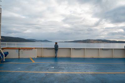 Rear view of woman standing by railing on nautical vessel