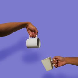 Low angle view of hand holding drink against blue background