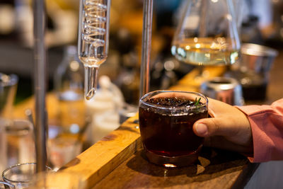 A close-up americano put ice in a transparent glass with the hand of a woman holding it. aroma.