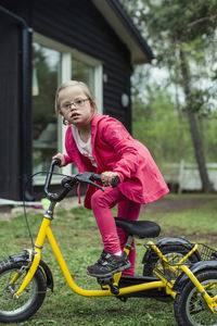 Portrait of girl with down syndrome riding bicycle in lawn