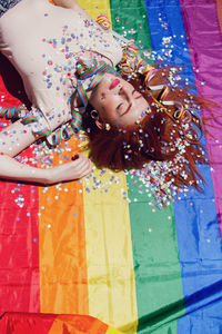 Young woman lying down on rainbow flag