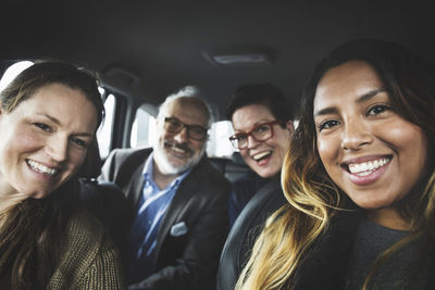 Portrait of happy people sitting in new car at showroom