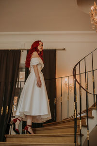 Red haired bride sitting in the armchair with bouquet