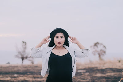 Portrait of woman standing on field against sky