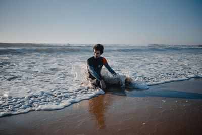 Full length of woman sitting on sea against clear sky