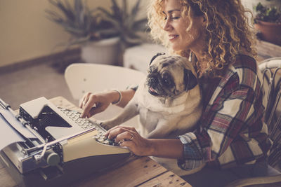 High angle view of woman with pug using typewriter