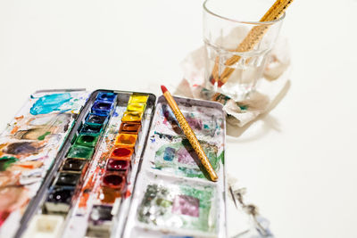 High angle view of paintbrushes on table against white background