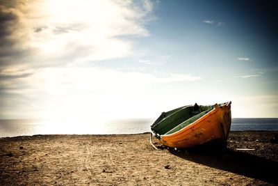 Abandoned boat on beach against sky